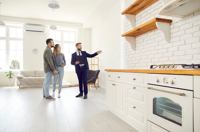 male real estate agent showing couple kitchen in house for sale